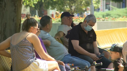 Oameni pe bancă, se relaxează în parc, unii cu mască alții fără