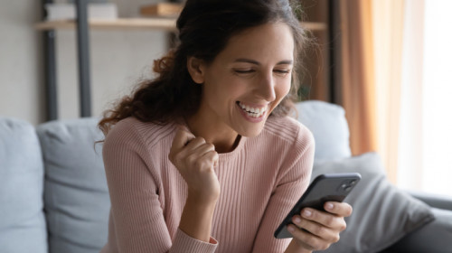 Femeie veselă, fericită citește un mesaj SMS pe telefonul mobil, veste bună, online, gadget, smartphone, notificare