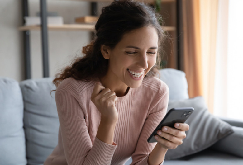 Femeie veselă, fericită citește un mesaj SMS pe telefonul mobil, veste bună, online, gadget, smartphone, notificare