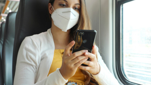 Femeie tânără studentă cu mască în tren, feroviar, CFR, telefon mobil, online, bilete de călătorie cu vagoane