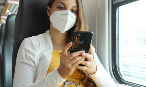 Femeie tânără studentă cu mască în tren, feroviar, CFR, telefon mobil, online, bilete de călătorie cu vagoane