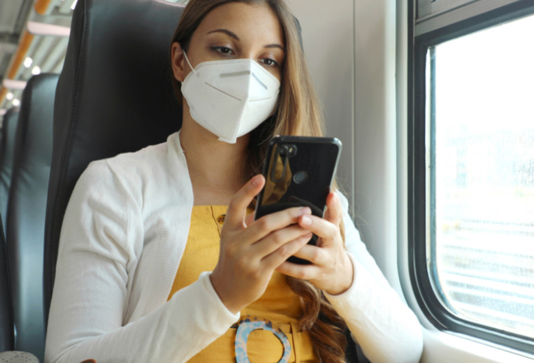 Femeie tânără studentă cu mască în tren, feroviar, CFR, telefon mobil, online, bilete de călătorie cu vagoane