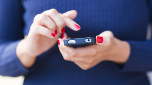 Femeie ține smartphone telefon mobil în mână, se uită pe Facebook, rețele de socializare, postează, internet, online, social media