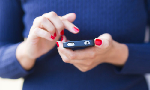 Femeie ține smartphone telefon mobil în mână, se uită pe Facebook, rețele de socializare, postează, internet, online, social media