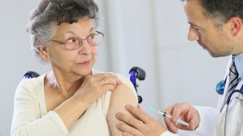 Persoană cu dizabilități, handicap în scaun cu rotile se vaccinează anti-coronavirus, COVID-19, SARS-CoV-2 cu medic, doctor și injecție, seringă, imunizare