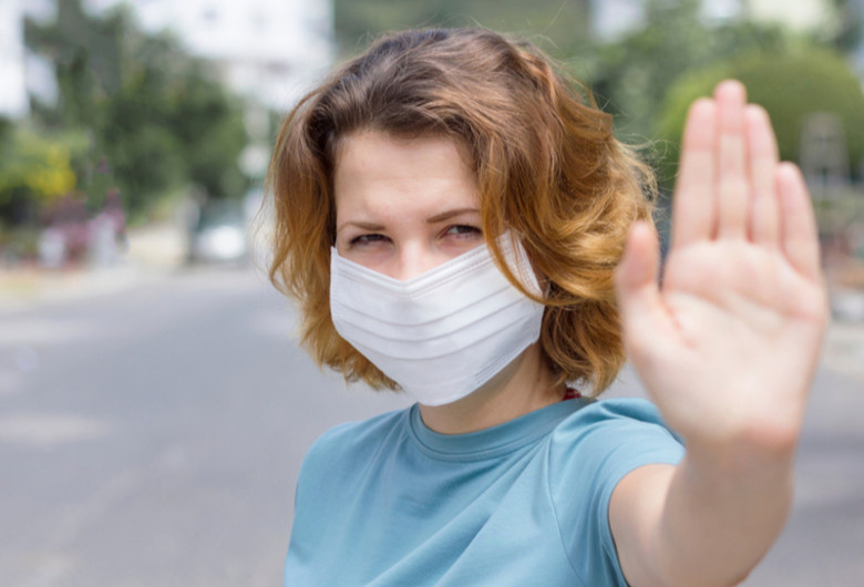 Femeie cu mască anti-COVID-19, coronavirus, SARS-CoV-2 arată mâna de a păstra distanța, fără gripă sau infecții respiratorii