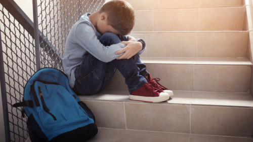Elev pe scări, la școală, bătut, agresat, bullying, violență, copil cu ghiozdan