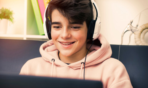 Școala online, băiat cu laptop în față se uită la orice, inclusiv filme porno, zâmbește, râde, imagini, social media, calculator