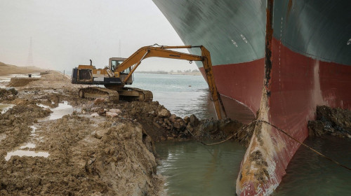 HANDOUT - 25 March 2021, Egypt, Suez: An excavator attempts to free the front end of the "Ever Given", a container ship operated by the Evergreen Marine Corporation. The state-run Suez Canal Authority (SCA) announced on Thursday that navigation through th
