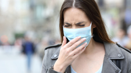 Femeie cu mască de COVID-19, coronavirus, tușește sau e răcită