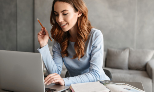 Tânără studentă sau elevă care se uită în laptop sau calculator online făcând teleșcoală