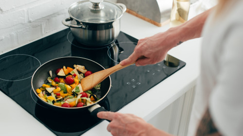 Gătește mâncare sănătoasă cu legume crude, vegetarian, organic în tigaie, pe plită cu inducție, aragaz, hrană în bucătărie