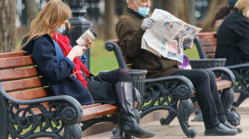 Oameni din Moscova, Rusia stau în parc pe băncuțe la relaxare, vacanță, zi liberă, sărbătoare legală, citesc ziar