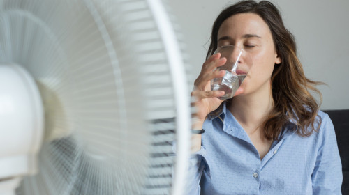 Femeie se răcorește cu apă și ventilator de vremea extrem de caldă cu caniculă și temperaturi ridicate