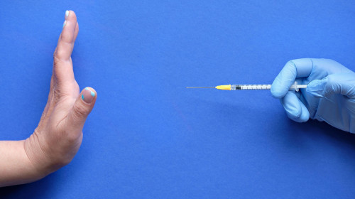 Vaccine refusal concept. Medic hand in glove with syringe. Hand refusing vaccination from measles or Covid-19. Anti-vaccination concept image.