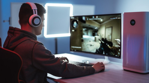 Tânăr joacă Counter-Strike pe calculator de esports cu purificator de aer lângă el