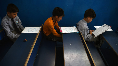 Elevi afgani în școală de educație cu învățământ primar în bănci