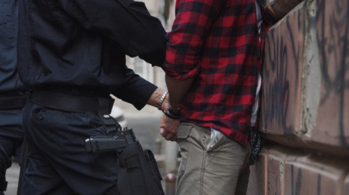 Polițiști sau jandarmi arestează un bărbat reținut infractor, căruia îi pun cătușe că e delincvent