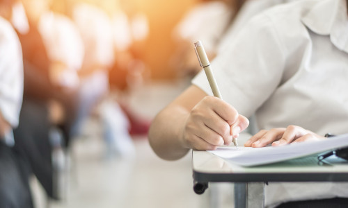 Exam with school student having a educational test, thinking hard, writing answer in classroom for university education admission and world literacy day concept