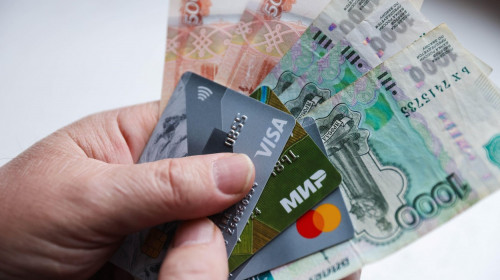 Grozny, Russia. 1st Mar, 2022. This image shows a person's hands holding money and Visa and Mastercard cards. On February 24, the United States announced it was imposing sanctions on major Russian banks, including Sberbank and VTB in response to the speci