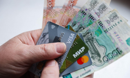 Grozny, Russia. 1st Mar, 2022. This image shows a person's hands holding money and Visa and Mastercard cards. On February 24, the United States announced it was imposing sanctions on major Russian banks, including Sberbank and VTB in response to the speci