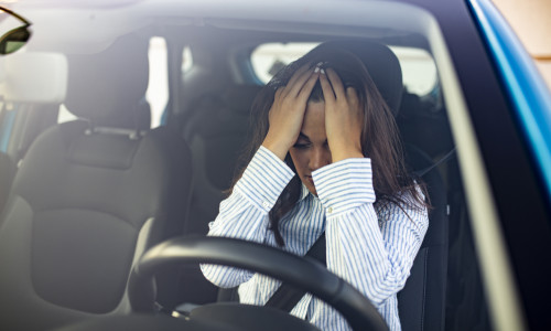 Young woman with hands on eyes sitting depressed in car