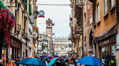 Verona, Italy - September 20, 2021: Tourists use their umbrellas to protect themselves from the rain during a visit to Verona on a cloudy day.