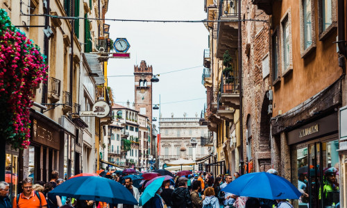 Verona, Italy - September 20, 2021: Tourists use their umbrellas to protect themselves from the rain during a visit to Verona on a cloudy day.