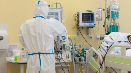 Male nurse with protective coverall clothing in intensive care unit in hospital. Dialysis machine, to which patient is connected. The patient fell i