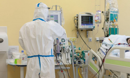 Male nurse with protective coverall clothing in intensive care unit in hospital. Dialysis machine, to which patient is connected. The patient fell i