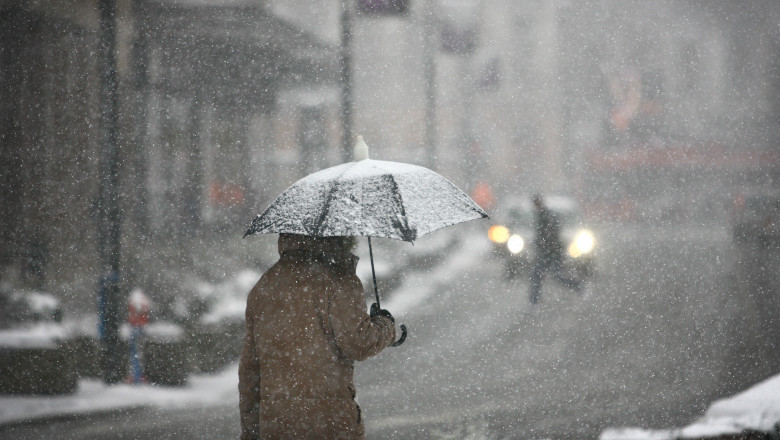 Man,With,Umbrella,During,Snow,Storm,In,The,Street