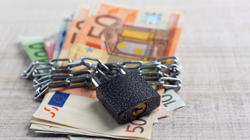 Euro,Banknotes,With,Lock,And,Chain,On,Wooden,Table,Background