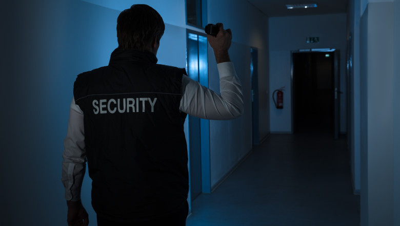 Rear,View,Of,A,Security,Guard,Standing,In,Corridor,Of