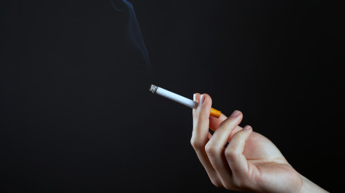 Female,Hand,Holding,A,Smoking,Cigarette,On,A,Dark,Background