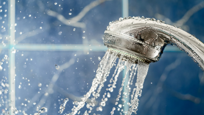 Shower,Head,With,Water,Splashing,Out,On,Blue,Background,,Copy