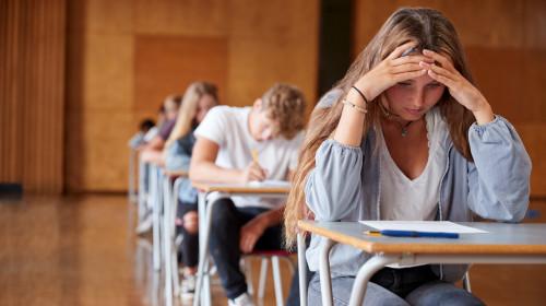 Anxious,Teenage,Student,Sitting,Examination,In,School,Hall