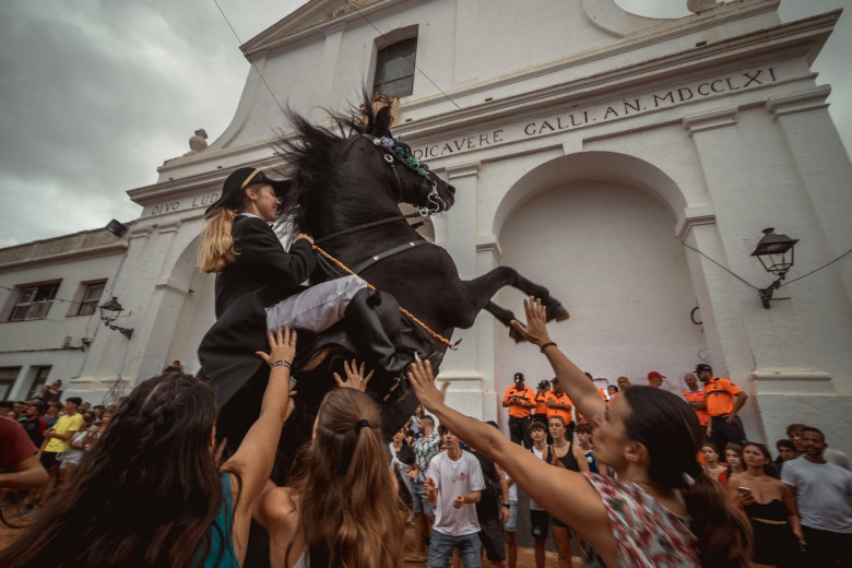 Sant Lluis, Spain. 27th Aug, 2023. A 'caixer' (horse rider) rears up on his horse surrounded by a cheering crowd during the traditional 'Jaleo' at the Sant Lluis Festival Credit: Matthias Oesterle/Alamy Live News