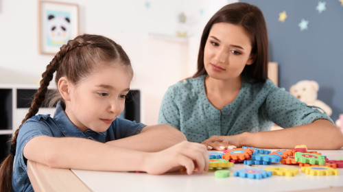 Young,Woman,And,Little,Girl,With,Autistic,Disorder,Playing,At