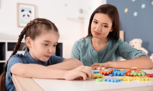 Young,Woman,And,Little,Girl,With,Autistic,Disorder,Playing,At