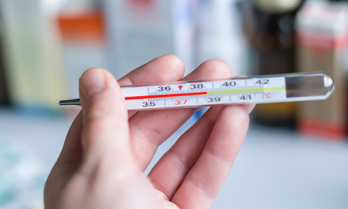A,Thermometer,With,A,High,Temperature,In,The,Hand,Against
