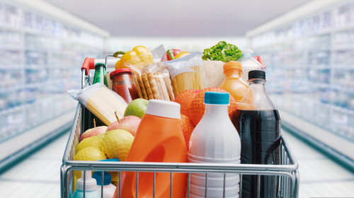 Shopping,Cart,Filled,With,Food,And,Drinks,And,Supermarket,Shelves