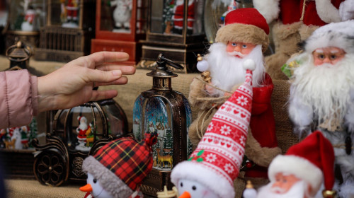 Shallow depth of field (selective focus) details with the hand of a woman reaching for Christmas gifts for sale in a Christmas market stall.