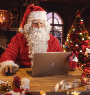 Merry,Santa,Claus,Sitting,Behind,A,Desk,And,Working,On