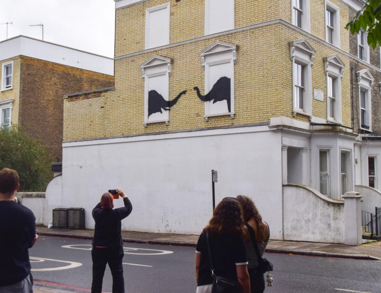 People take photos of a new artwork, confirmed to be by Banksy, on a wall of a house in Chelsea. The artwork, depicting a pair of elephants, is the second new artwork in London in two days by the elusive street artist.