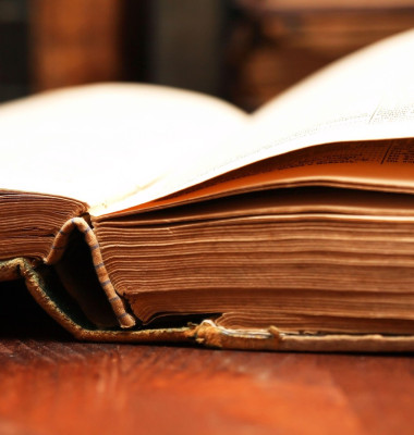 Very old open books on wooden table against background with another books