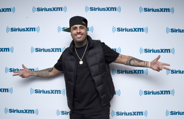 nicky jam cu sapca si vesta negre, cu bratele deschise, pozeaza la un eveniment sirius xm