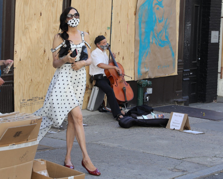 Famke Janssen takes pictures of art on boarded stores windows in Soho, NYC