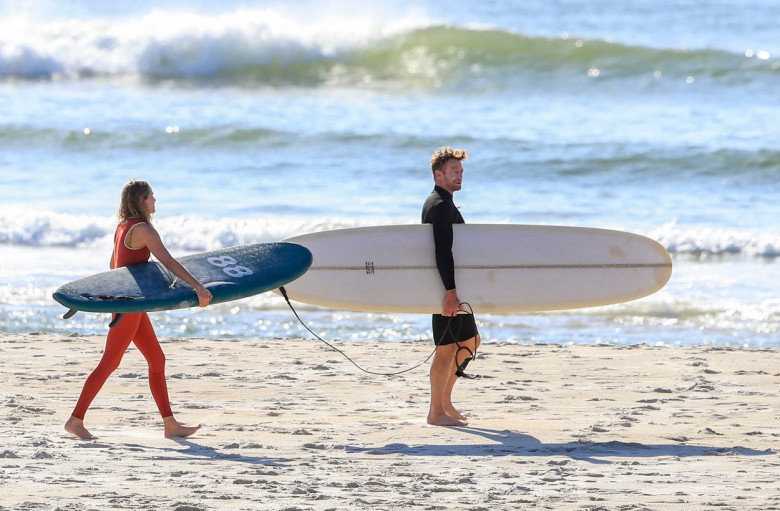 EXCLUSIVE: *NO DAILYMAIL ONLINE* Simon Baker Suffers A Cheeky Wetsuit Wardrobe-Malfunction During A Surf Session With Girlfriend Laura May Gibbs In Byron Bay