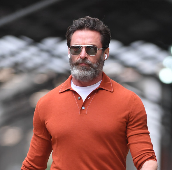 Hugh Jackman wears an orange pullover shirt and brown suede shoes in New York City