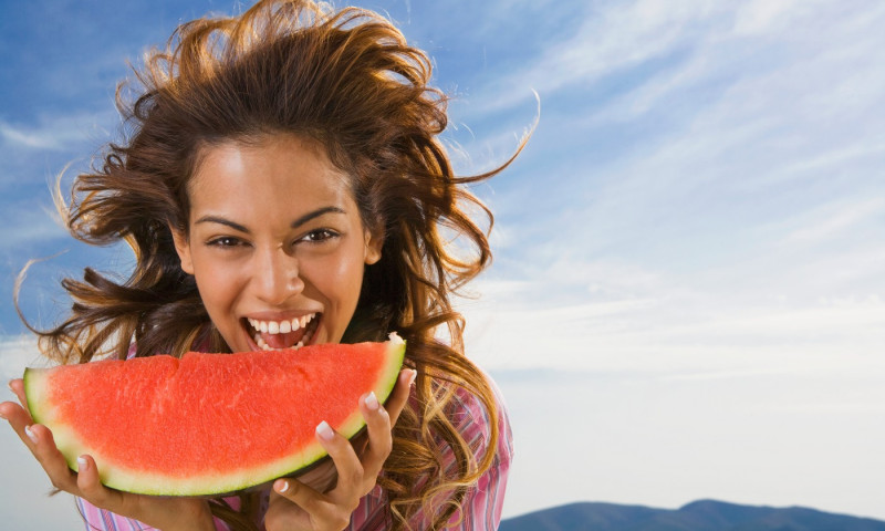 Woman laughing and eating watermelon